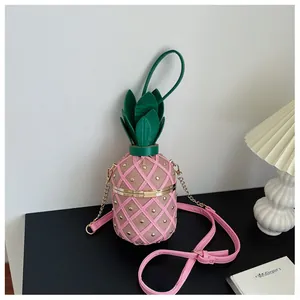 Détail du sac seau ananas rose avec clous dorés et décoration de feuilles vertes