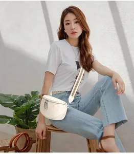 Détail d'un sac banane en cuir beige avec une large bandoulière rayée de style sport