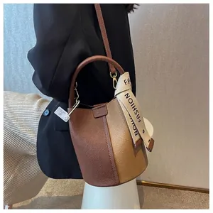 Contrast color bucket bag with lychee texture and ribbon detail worn by model