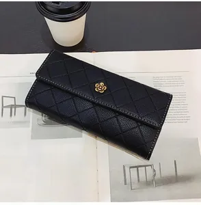 Long black wallet with diamond quilting and gold floral clasp on a fashion magazine