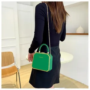 Detailed view of emerald green hard shell fashion box bag with gold metal frame and chain