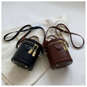 Détail de sacs seaux vintage en cuir noir et marron avec poignées enroulées de foulard