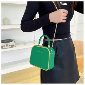 Detail of green octagonal hard shell bag with golden chain strap and fashion logo