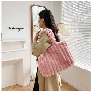 Détail d'un cabas rose en peluche avec poignée à bulles et texture à rayures