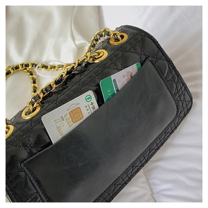 Detail view of the black quilted crossbody bag showing the back card pocket and chain strap