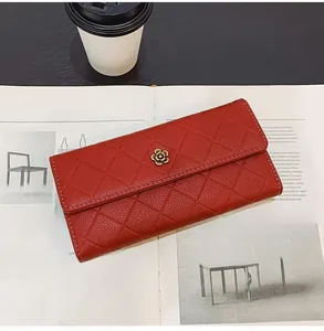 Detail of red quilted leather long wallet with golden flower clasp on a magazine