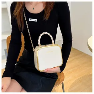 Detail of off-white hexagonal hard shell box bag with gold metal trim and woven handle