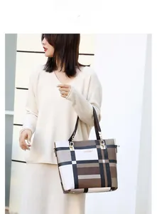 Detail of checkered tote bag with brown handles and golden hardware for women