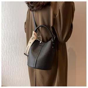 Detail of black lychee grain bucket bag featuring a detachable branded wide shoulder strap