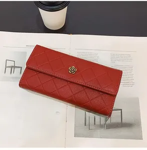Detail of red quilted long wallet featuring a golden camellia flower logo on a magazine