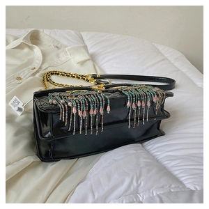 Close-up of black patent leather bag featuring colorful rhinestone tassels and gold chain