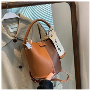 Close-up of litchi grain leather bucket bag with fashion strap and color block design