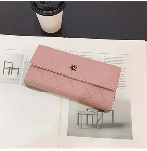 Detail of mauve long wallet with diamond quilted pattern and gold flower accent on magazine