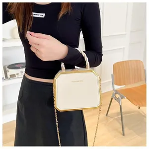 Detail of octagonal cream box bag with gold metal trim and detachable chain strap