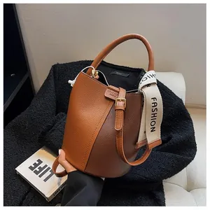 Detail of a brown bucket bag with lychee pattern leather and a wide branded shoulder strap