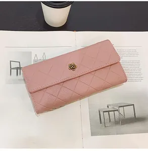Detailed close-up of pink quilted long wallet with elegant metal flower clasp on a magazine