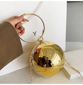Detailed view of a metallic gold spherical clutch bag with round handle and gold chain