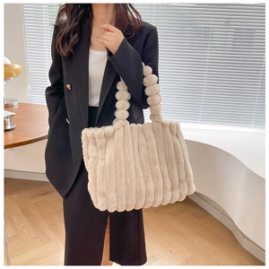 Détail du sac cabas en peluche avec poignée à pompons et texture rayée en fausse fourrure