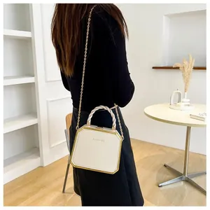 Detail of white hexagonal chain bag with gold metal trim and woven handle