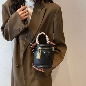 Sac seau noir avec poignée en soie léopard et détails dorés porté avec un blazer