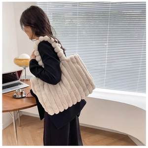 Sac cabas en fausse fourrure beige avec texture rayée et pompons dans un décor de bureau