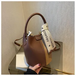 Detailed close-up of brown and beige bucket bag with stylish fashion ribbon handle