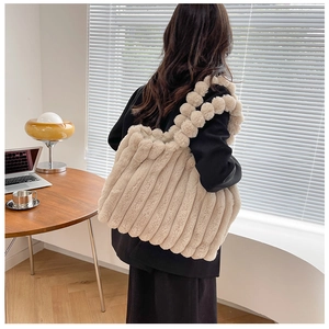 Détail du sac cabas en peluche avec texture rayée et bandoulière décorative à pompons