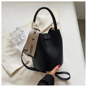 Detailed macro of black pebbled leather bucket bag with a branded wide fabric strap