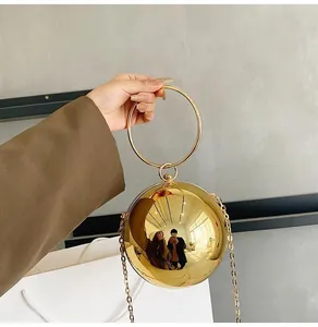 Macro shot of polished gold spherical handbag featuring mirror finish and ring handle