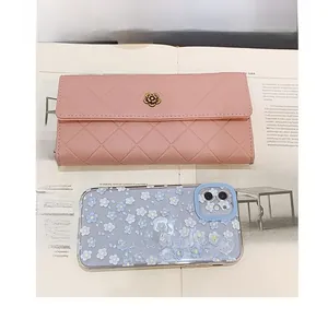 Pink quilted long wallet with golden flower clasp shown next to a smartphone