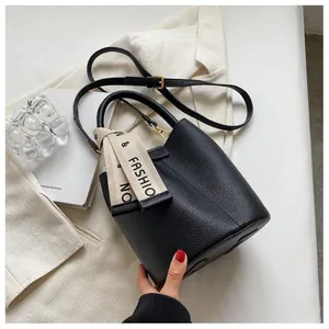 Close-up of black lychee grain leather bucket bag with silk scarf and gold hardware