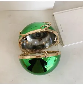 Detailed top view of a green metallic and transparent spherical clutch bag with gold handle