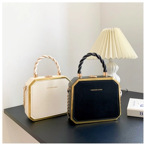 Fashionable octagonal hard shell handbag in black and white with gold chain and spiral handle