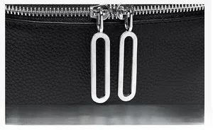Détail des fermetures éclair en métal argenté sur un sac en cuir noir à grain de litchi
