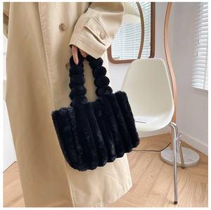Détail d'un sac cabas en fausse fourrure noire avec rayures et poignée à pompons