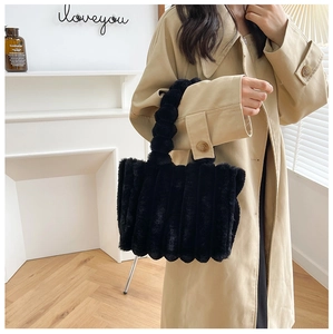 Détail du sac à main en fausse fourrure noire à rayures verticales porté avec manteau