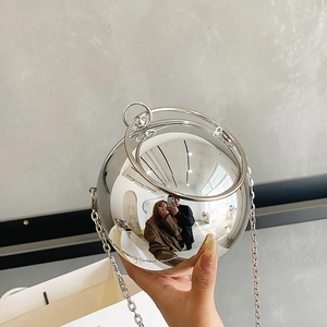 Polished silver spherical evening bag with metal ring handles and long chain strap