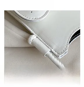 Gros plan sur les coutures précises et la poignée tressée de ce sac à main blanc