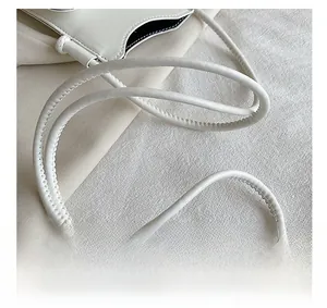 Détail de la bandoulière tubulaire en cuir blanc avec coutures fines pour ce sac à main