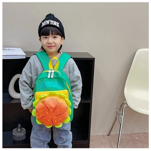 Détail d'un sac à dos burger vert mignon avec poche orange porté par un enfant