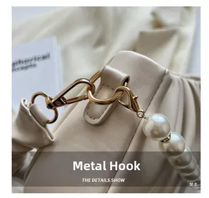 Close-up of creamy faux leather cloud bag featuring gold hardware and large pearl strap