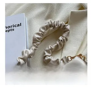 Detail of soft beige leather pleated shoulder strap and premium gold metal hardware hooks