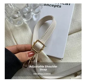 Detail of adjustable off-white leather strap with gold buckle and spring hook hardware