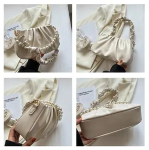 Detail view of beige pleated cloud bag with pearl handle and ruffled shoulder strap