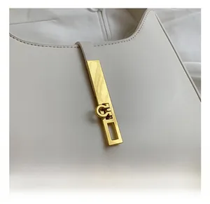 Close-up of the elegant rectangular golden metal buckle on a cream leather shoulder bag