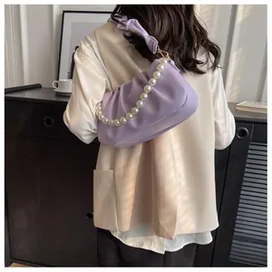Close-up of lavender pleated cloud bag with elegant white pearl chain and soft leather