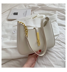 Detail of cream hobo bag with gold metal lock and chain strap on aesthetic background