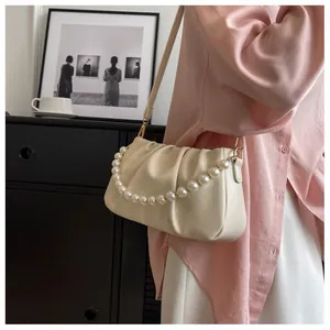 Detail of cream pleated cloud bag with elegant pearl chain and soft leather texture