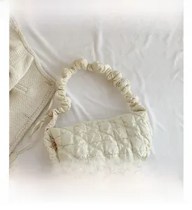 Close-up of quilted puff shoulder bag in cream with ruffled handle and zipper detail