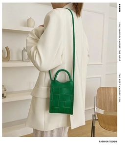 Detail of green woven leather mobile phone crossbody bag with slim shoulder strap
